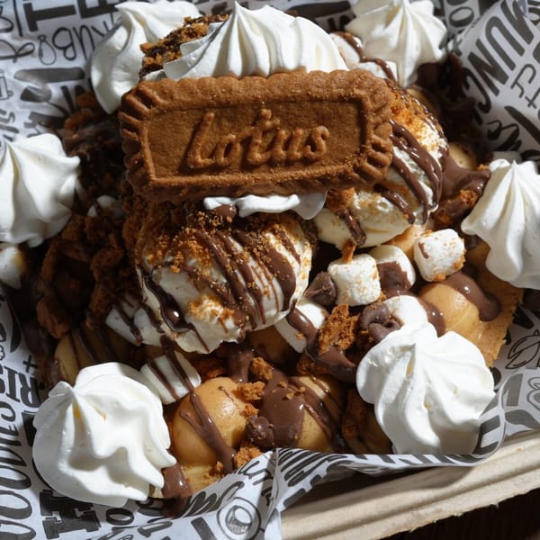 Bubble waffle dessert with ice cream, chocolate drizzle, marshmallows, whipped cream, and a Lotus Biscoff cookie.