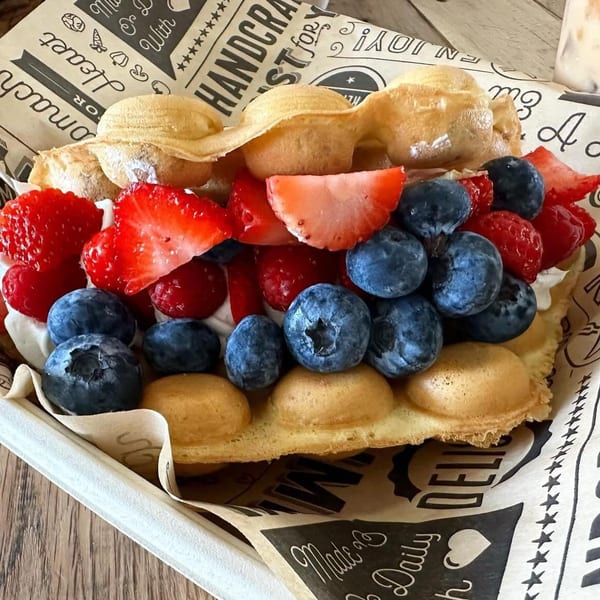 A bubble waffle filled with whipped cream, fresh strawberries, blueberries, and raspberries.